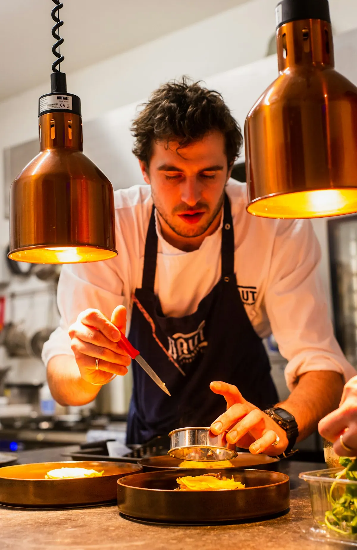 A chef finishes a dish in the kitchen.